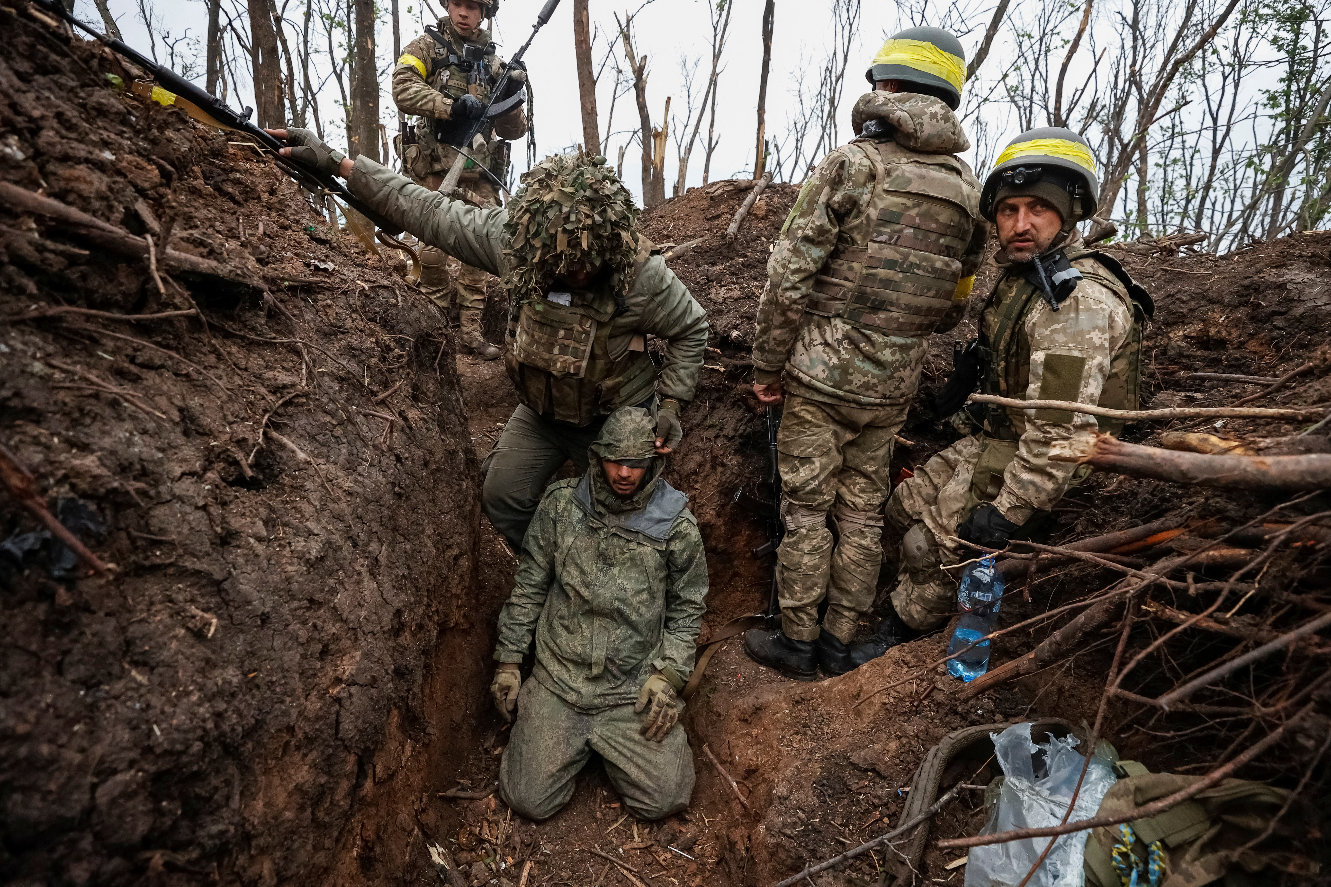 Soldados ucranianos permanecen junto a un militar del ejército ruso capturado, según ellos, en posiciones recientemente ganadas en una ofensiva, mientras continúa el ataque de Rusia a Ucrania, cerca de la ciudad de Bakhmut (Reuters)